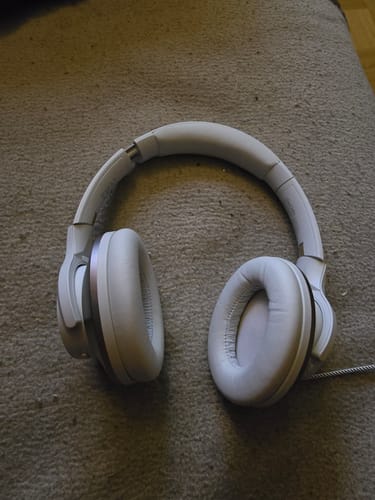 Silver Oneodio headphones resting on a carpet